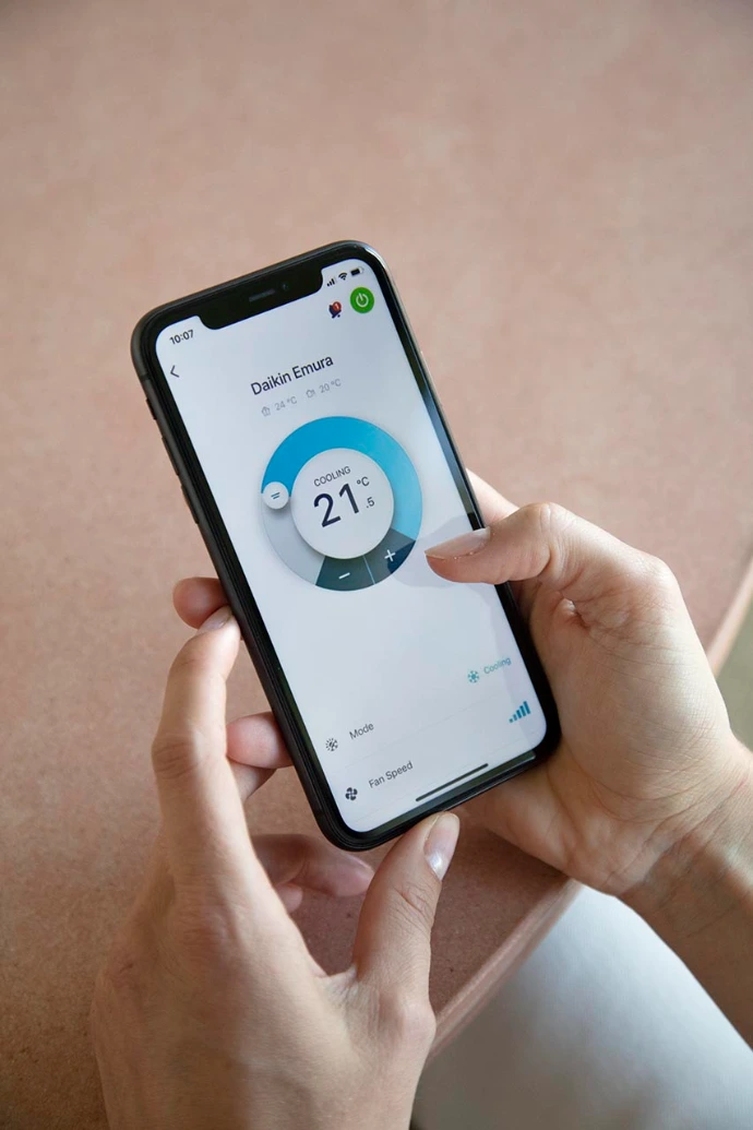Homeowner controlling their home air conditioning and heating system via a smartphone app.